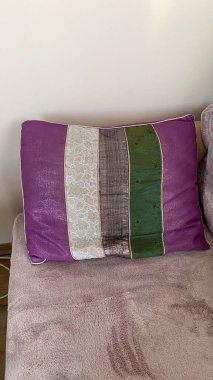 A purple and green pillow sitting on top of a couch. clipart