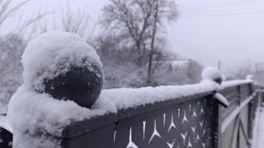 Metal bir çitin tepesinde karla kaplı bir top