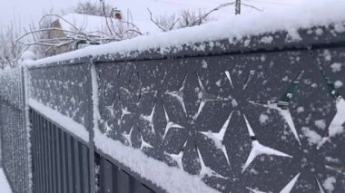 Ağacın yanındaki karla kaplı metal bir çit.