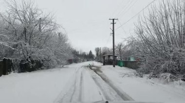 Arkasında ağaçlar ve elektrik hatları olan karla kaplı bir yol.