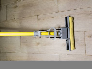 Sarı saplı, ahşap zeminde sarı bir paspas..