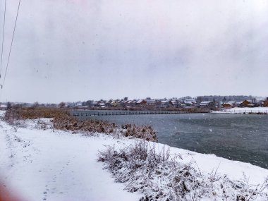 Arkasında bir nehir olan karlı bir manzara..