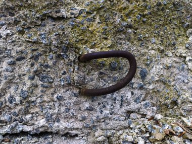 A rusty hook on a rock with moss growing on it clipart