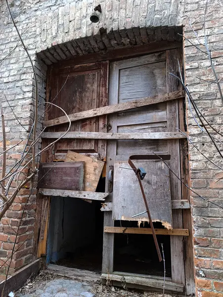Terk edilmiş bir binanın eski ahşap kapısı ve kırık bir penceresi var.
