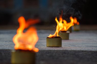 Beton zeminin üstünde yanan bir grup mum..