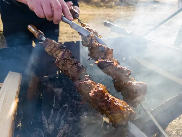 Birisi ızgarada bıçakla et pişiriyor..