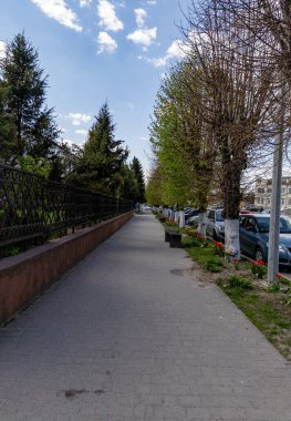 Çitin yanında park halindeki arabalarla dolu bir kaldırım..