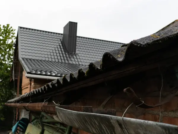 Tuğla bir binanın yanında metal oluğu olan bir çatı..