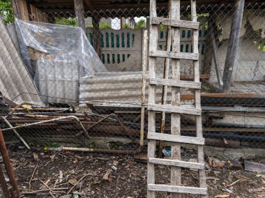 Zincirli tel örgüye dayanmış tahta bir merdiven..