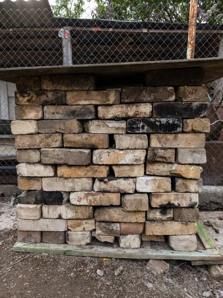 Tahta bir paletin tepesinde duran tuğla yığını..