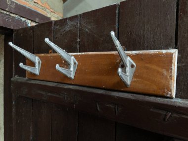 Üzerinde üç metal kanca olan tahta bir raf..
