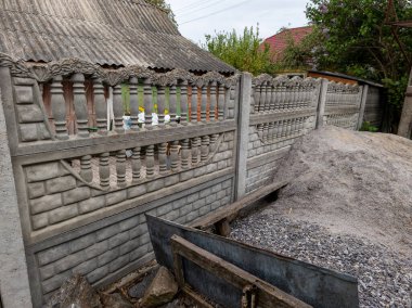 Metal çitli beton bir duvar ve bir yığın toprak..