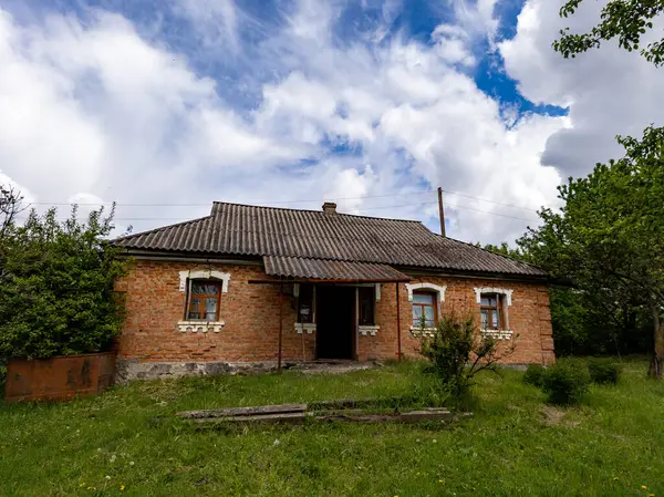 Çimenli bir tarlanın ortasında küçük bir tuğla ev..