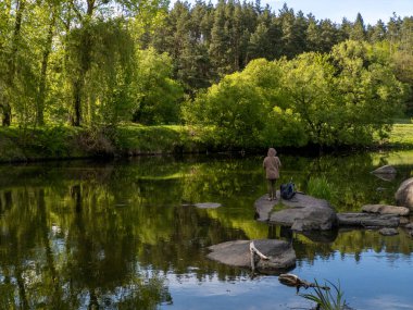 Gölün ortasındaki bir kayanın üzerinde duran bir insan..