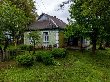 Çitin yanındaki çimenli bir alanda küçük bir ev..