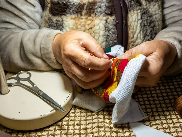 Bir kadın makasla bir kumaş parçası üzerinde çalışıyor..