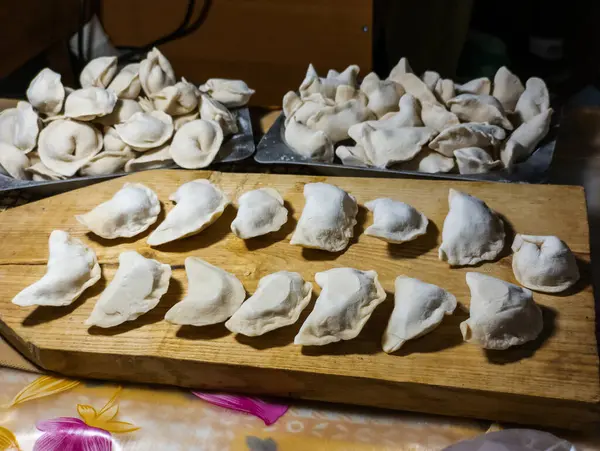 Masanın üstünde bir sürü hamur köftesi olan tahta bir tahta kesme tahtası..