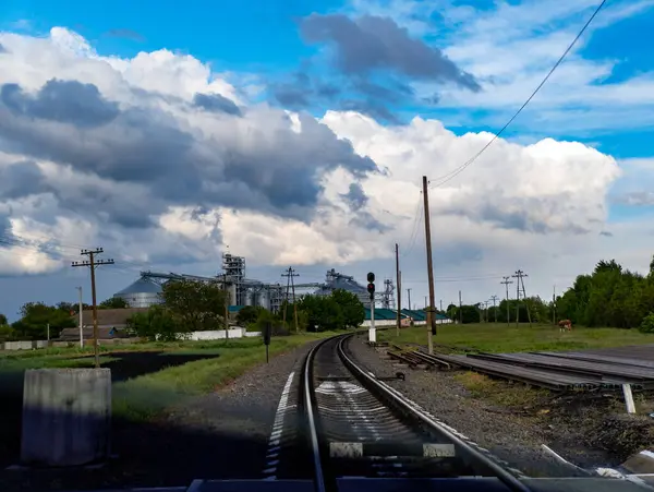 Arka planda fabrikası olan bir tren yolu manzarası..