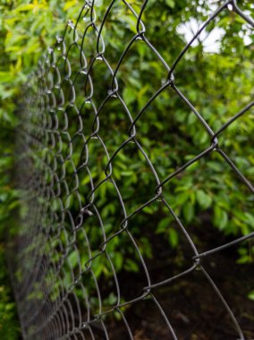 Üzerinde su damlaları olan ızgara çiti..