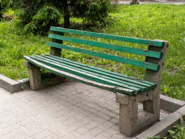 Parktaki kaldırım taşlarının üzerinde duran yeşil bank..