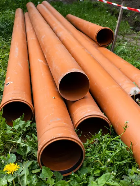 Bir grup turuncu boru çimlerin üzerinde yatıyor..