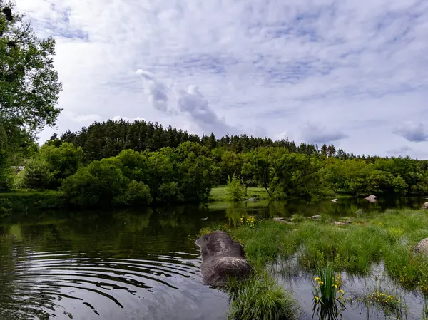 Gölün ortasında ağaçlarla çevrili büyük bir kaya..
