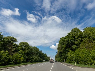 Tıbbi yardım ambulansı her iki tarafta ağaçlarla birlikte yolda ilerliyor..