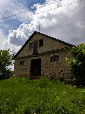 Çimenli bir arazinin ortasında duran eski bir taş bina..