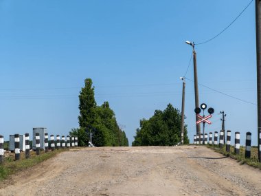 Kirli kırsal bir yolda tren yolu ve işaret diliyle kesişiyor..