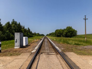 Çimenli bir arazinin ortasında tren yolu..