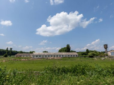 Su kulesi ve ağaçları olan büyük beyaz bir bina..