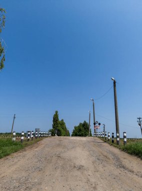 Kirli kırsal bir yolda tren yolu ve işaret diliyle kesişiyor..