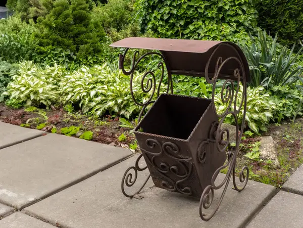 Bahçedeki kaldırımda duran metal çöp tankı..