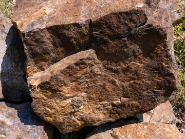 Büyük bir kaya yığını üzerinde oturuyordu..