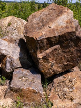 Çimlerle kaplı bir arazinin tepesinde duran büyük bir kaya yığını..