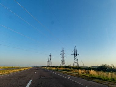 Uzakta elektrik hatları olan uzun ve boş bir yol..