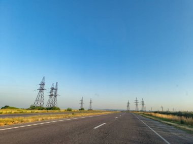 Uzakta elektrik hatları olan uzun ve boş bir yol..