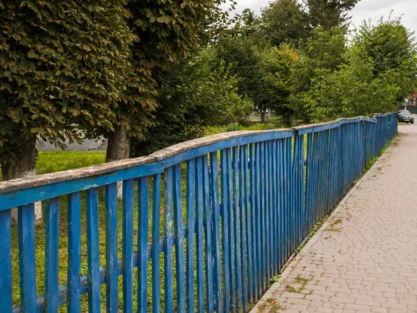 Yolun kenarında, kaldırımın yanında mavi bir çit..