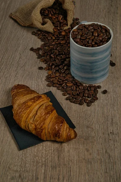 茶色のローストコーヒー豆のトップビューは 完全なコーヒーマグカップとビスケット イメージとテーブルの上にこぼれた ロイヤリティフリーのストック画像