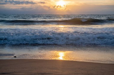 Gün batımı, güneş ışığı sahildeki dalgalara yansıyor. Yüksek kalite fotoğraf