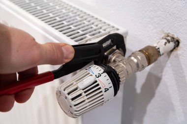 Hand with water pipe pliers on radiator thermostat. High quality photo