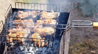 Tasty chicken wings cooking on barbecue grill, outdoors. Roasted chicken meat, closeup