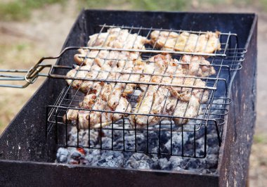 Izgarada pişen leziz tavuk kanatları, açık havada. Kızarmış tavuk eti, yakın plan.