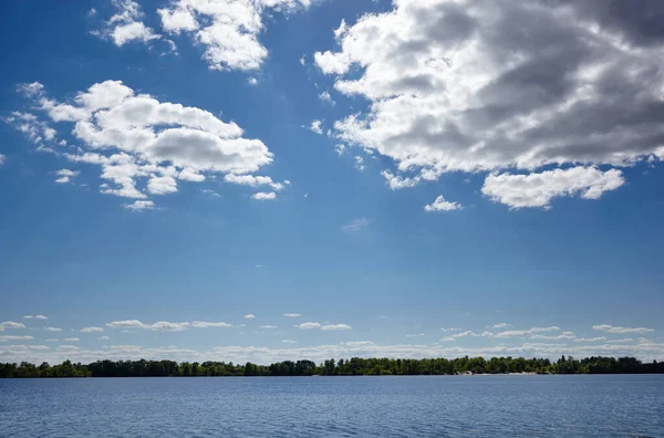 Beautiful river landscape. Lake surface on a sunny perfect day. The surface of the water against the background of trees and a blue sky. Blurred image, selective focus