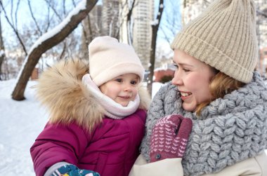 Anne ve kızı Noel ve yeni yıl tatillerinde kış şehir parkında yürüyorlar. Ebeveyn ve küçük çocuk dışarıda eğleniyor.