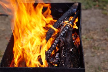 Yanan kırmızı kıvılcımlar ateşten uçar. Işıl ışıl yanan kömür ve yakacak odunları olan ızgara ızgarası.