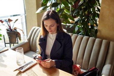 Güzel, çekici bir kadın kafede kahve bekliyor. Kahve molası. Pencereden sabah ışığı düşüyor.