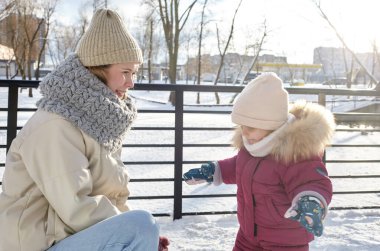 Anne ve kızı Noel ve yeni yıl tatillerinde kış şehir parkında yürüyorlar. Ebeveyn ve küçük çocuk dışarıda eğleniyor.