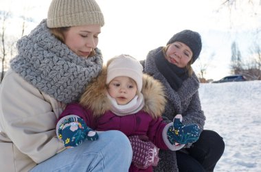 Büyükanne, anne ve kız Noel ve yeni yıl tatillerinde kış şehir parkında yürüyorlar. Ebeveyn ve küçük çocuk dışarıda eğleniyor.
