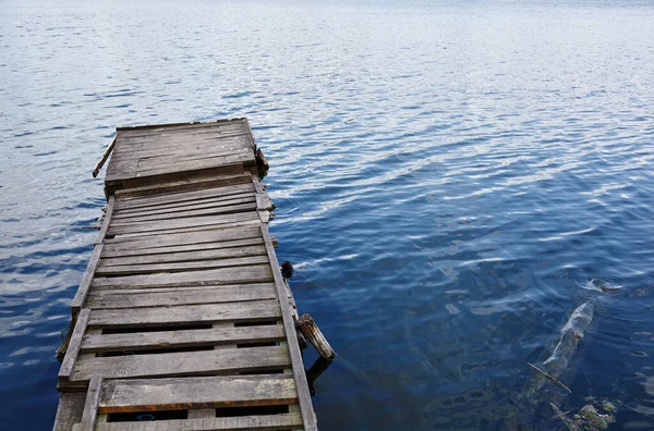 stock image wooden pier on the river bank. Ripple on the water surface. Blurred image, selective focus